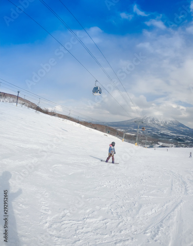 Views of Mount Fuji in Japan . Free ride snowboarder downhill on a snow-covered slope leaving behind mountains against the blue sky . Winter vacation and sport concept