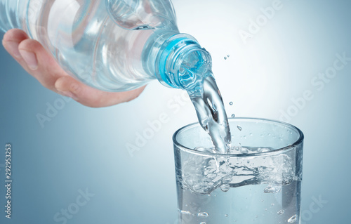 pouring water into a glass on blue background