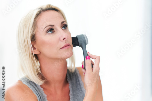 Adult beautiful woman cleaning face with brush