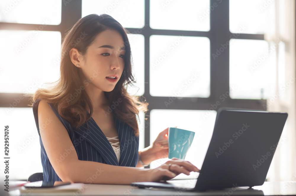 Young Asian female sitting and using Laptop computer in the office. Young Asian female sitting and using Laptop computer in the office.
