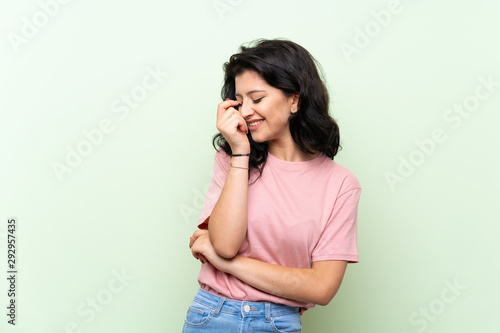 Young woman over isolated green background smiling a lot
