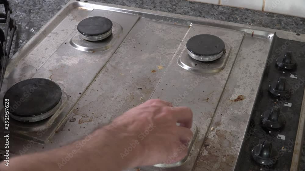 Man preparing dirty gas stove for cleaning by removing gas stove top