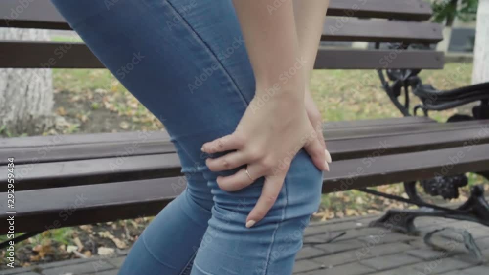 Woman standing up from bench feeling sharp knee pain in park