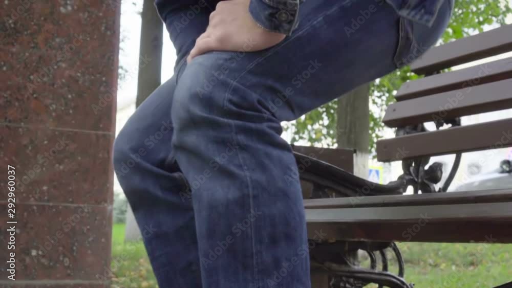 Man standing up from bench feeling sharp knee pain in park, osteoarthritis, injury Man standing up from bench feeling sharp knee pain in park, osteoarthritis, injury