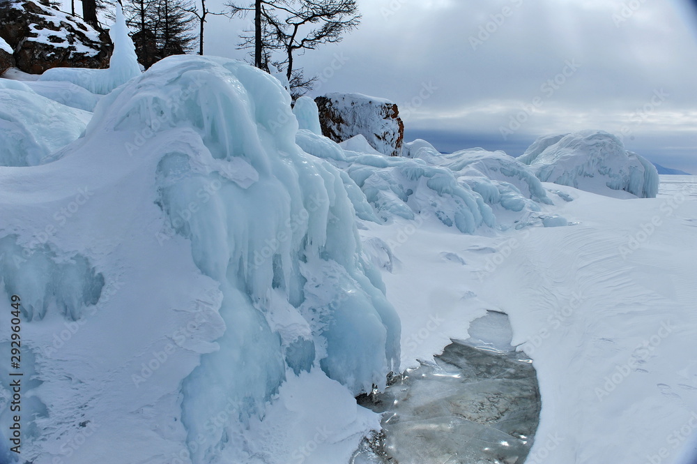 Lake Baikal in the winter. Crystal clear ice covers the lake. Coastal stones and rocks are covered with a layer of ice. Lake Baikal in the winter. Crystal clear ice covers the lake. Coastal stones and rocks are covered with a layer of ice.