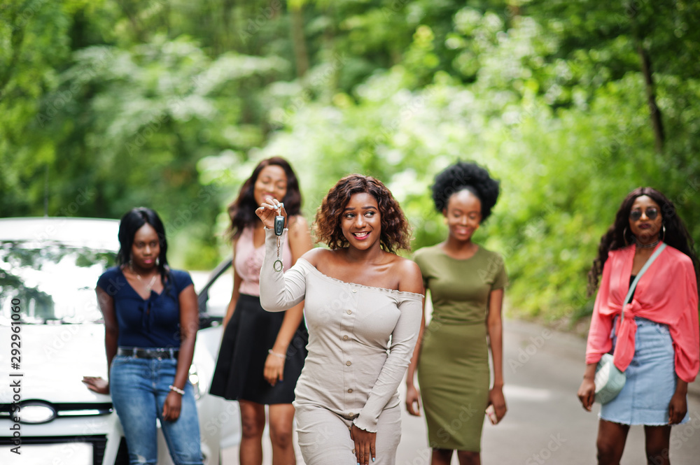 Group of five happy african american girls posed against car, one of them show keys. Group of five happy african american girls posed against car, one of them show keys.