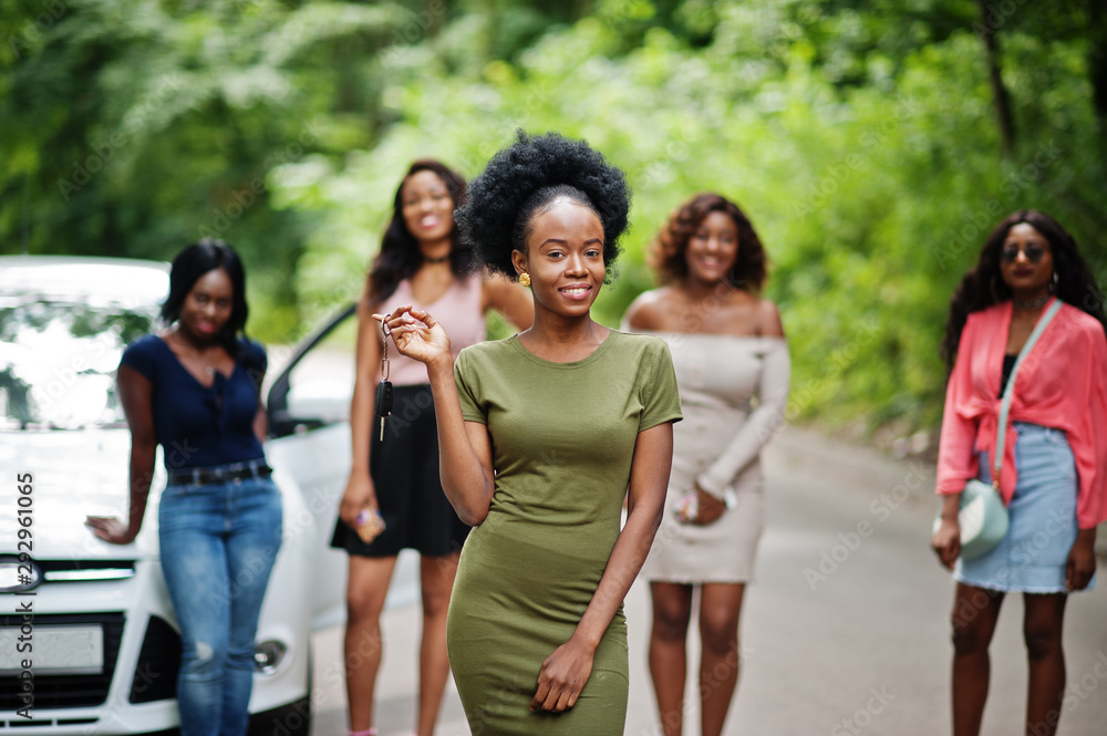 Group of five happy african american girls posed against car, one of them show keys. Group of five happy african american girls posed against car, one of them show keys.