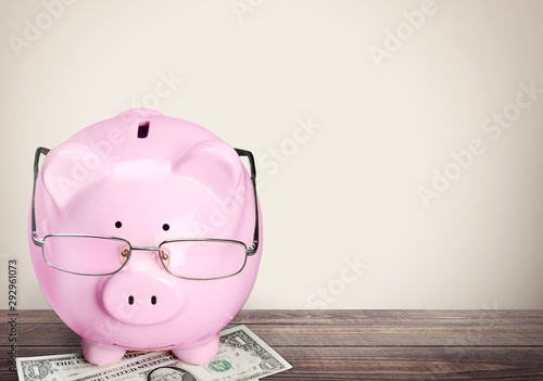 Blue piggy bank in glasses on background