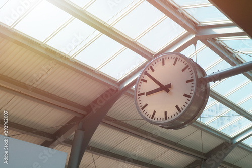 White round clock installed at the top near the glass roof at train station for decoration interior and showing time to passengers Time management and ceiling structure concept