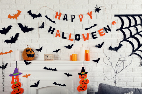 Halloween decorations on white fireplace with orange pumpkins and paper bats