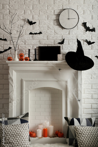 Halloween decorations on white fireplace with soft pillows and candles photo