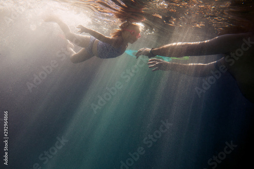 A little girl swimming to her dad shot from underwater photo