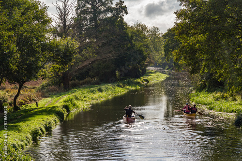 Middle aged senior people kayak or canoe down a beautiful river in the countryside in Surrey, England
