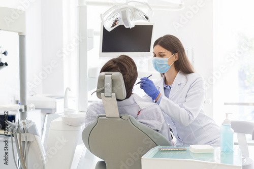 Young female dentist making treatment to patient