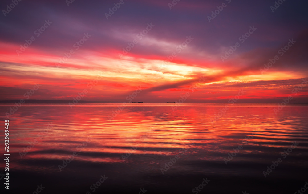 Fiery dramatic landscape with the sea, beautiful sky and ships. Dawn. small waves, almost calm.