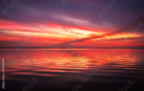 Fiery dramatic landscape with the sea, beautiful sky and ships. Dawn. small waves, almost calm. © es0lex