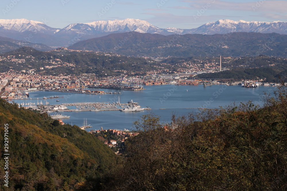 Panoramic view of La Spezia in Liguria shot from above. A cruise ship in the port, numerous moored sailboats and commercial port cranes..
