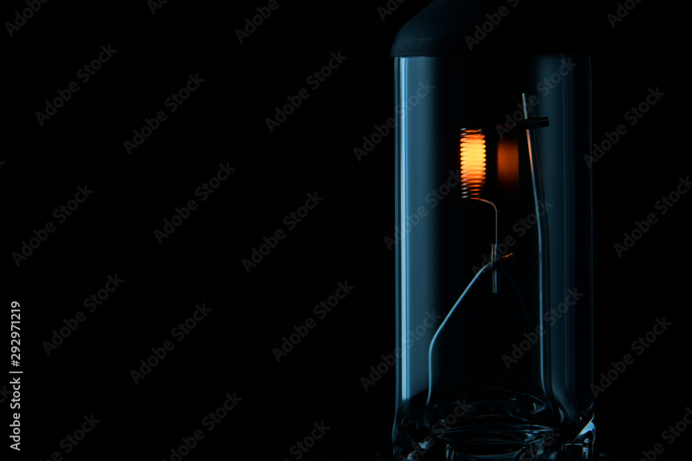 Spare car headlight lamp on black background.Lighted car light bulb in the dark with place for text.