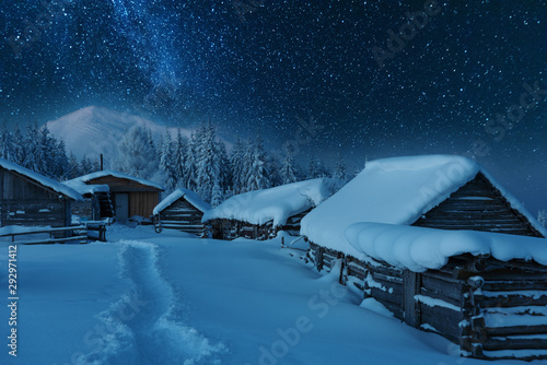 Fairytale landscapes of the winter Carpathian Mountains with a charming milky way in the sky tourist tents and snowy houses in the valleys