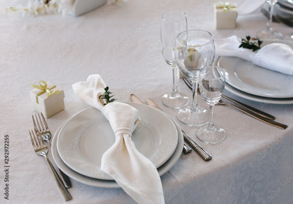 table setting: plates, forks, knives, knotted napkin, glasses, small gift box