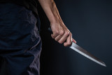 Man's hand holds a knife on dark background with seletive focus Violence and murder. thief, killer, rapist, maniac