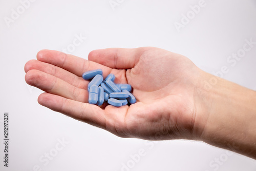 Blue pills in man s hand on white background