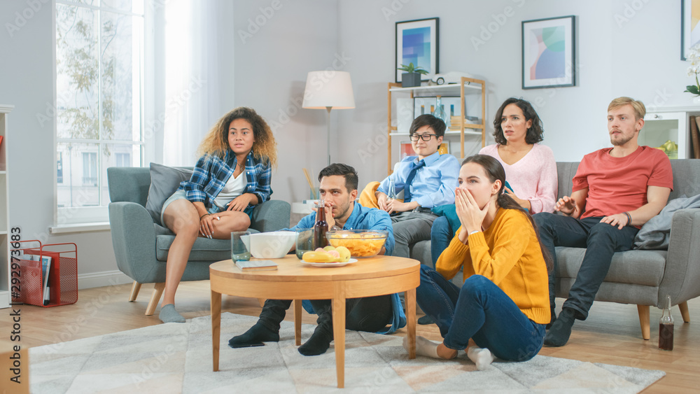 At Home Diverse Group Friends Watching TV Together, Getting Emotionally Terrified and Horrified by the Content of the TV. Young People Are Scared After Watching News or Horror Movies. At Home Diverse Group Friends Watching TV Together, Getting Emotionally Terrified and Horrified by the Content of the TV. Young People Are Scared After Watching News or Horror Movies.