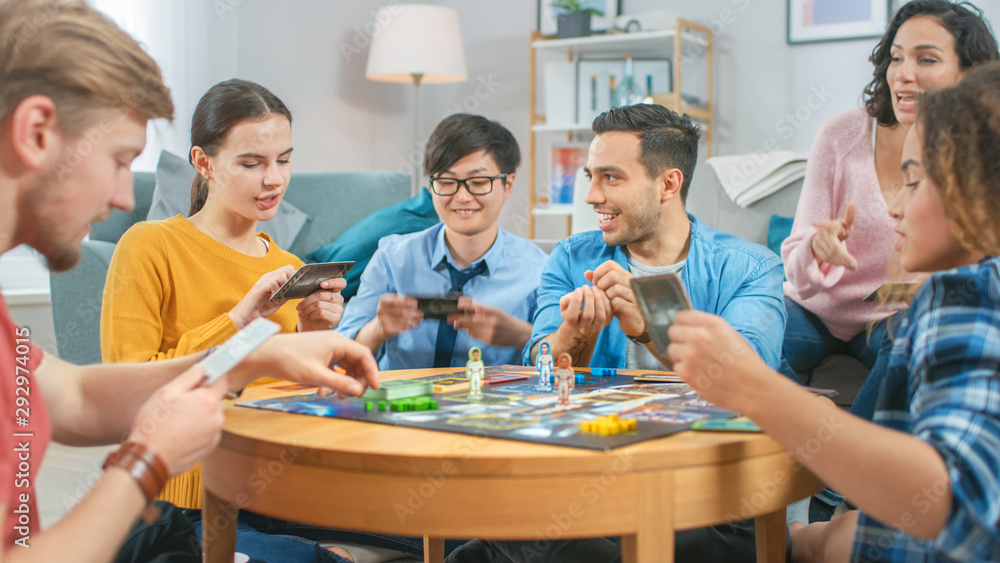 Diverse Group of Guys and Girls Playing in a Strategic Board Game with Cards and Dice. Cozy