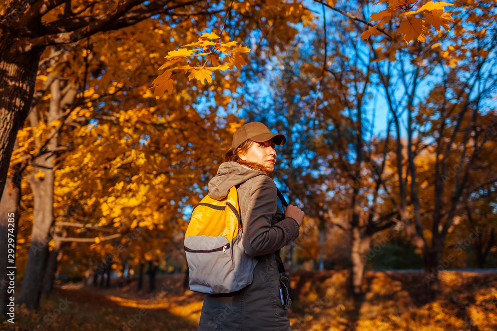 Tourist with backpack walking in autumn forest. Young woman travel at sunset Tourist with backpack walking in autumn forest. Young woman travel at sunset