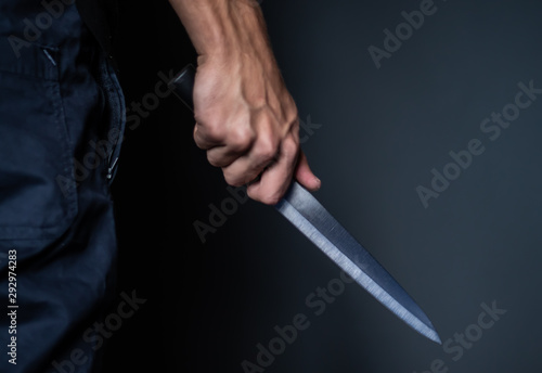 Man's hand holds a knife on dark background with seletive focus Violence and murder. thief, killer, rapist, maniac