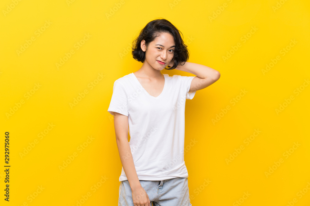 Asian young woman over isolated yellow wall having doubts Asian young woman over isolated yellow wall having doubts