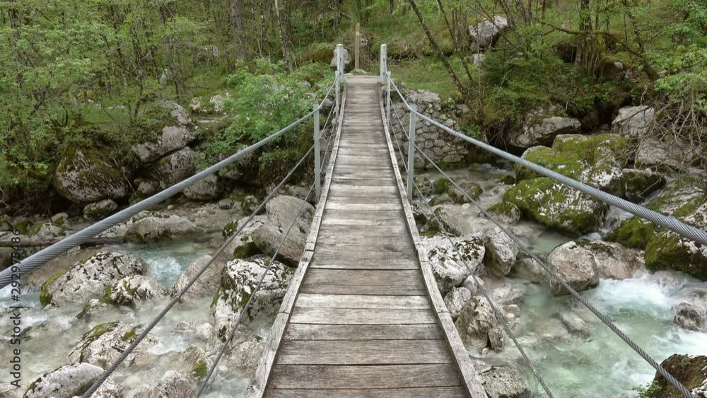 Suspension bridge through a mountain river in Slovenia at spring, 4k Suspension bridge through a mountain river in Slovenia at spring, 4k