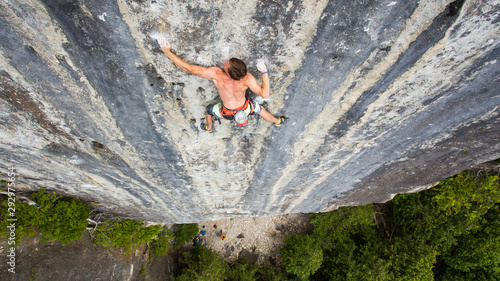 Strong shirtless rock climber on a tall striped wall, strong shoulders