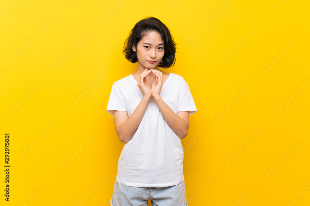 Asian young woman over isolated yellow wall scheming something Asian young woman over isolated yellow wall scheming something