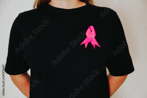 Girl in black t-shirt with a symbol of breast cancer a pink ribbon on her chest. Cancer concept. Suffering from cancer concept.
