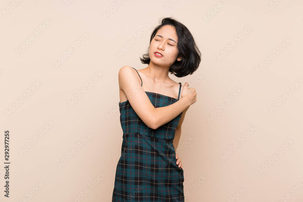 Asian young woman over isolated yellow wall suffering from pain in shoulder for having made an effort Asian young woman over isolated yellow wall suffering from pain in shoulder for having made an effort