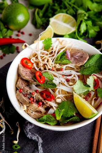 Pho Noodle Soup on dark table. Beef with Chilli, Basil, Rice Noodles, Bean Shoots showing noodles