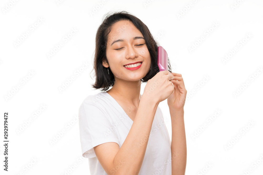 Asian young woman over isolated background with hair comb