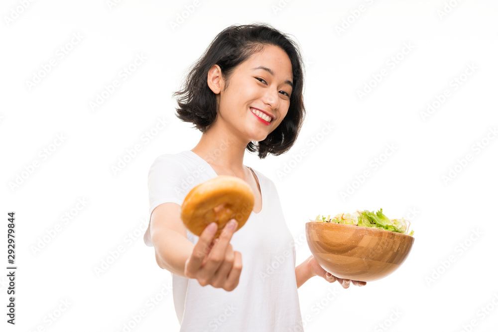 Asian young woman over isolated background with salad and donut Asian young woman over isolated background with salad and donut