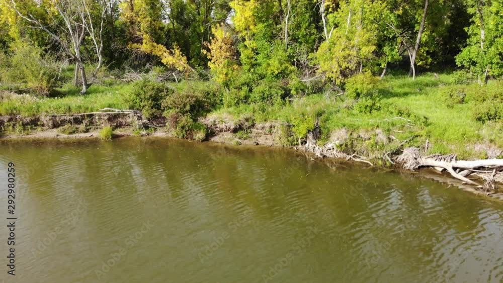 Drone rising above a muddy river to reveal a brightly colored forest and farm fields with a large lake in the background. Drone rising above a muddy river to reveal a brightly colored forest and farm fields with a large lake in the background.