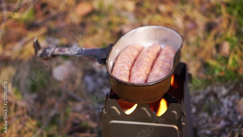 Cooking sausages on twig stove outdoors, close up