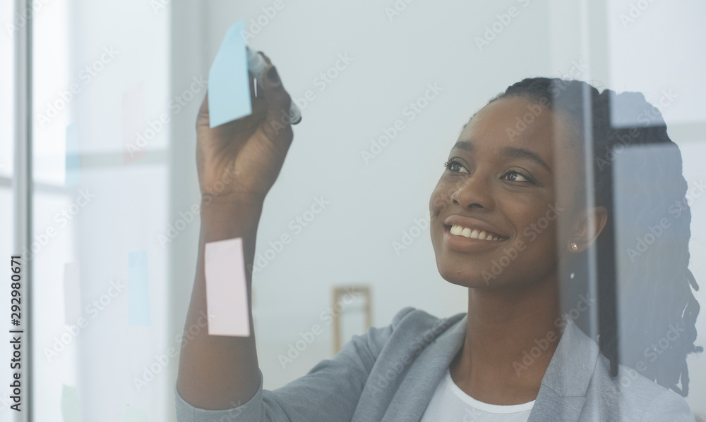 Businesswoman Reading Colorful Notes On Glass Board In Office Businesswoman Reading Colorful Notes On Glass Board In Office