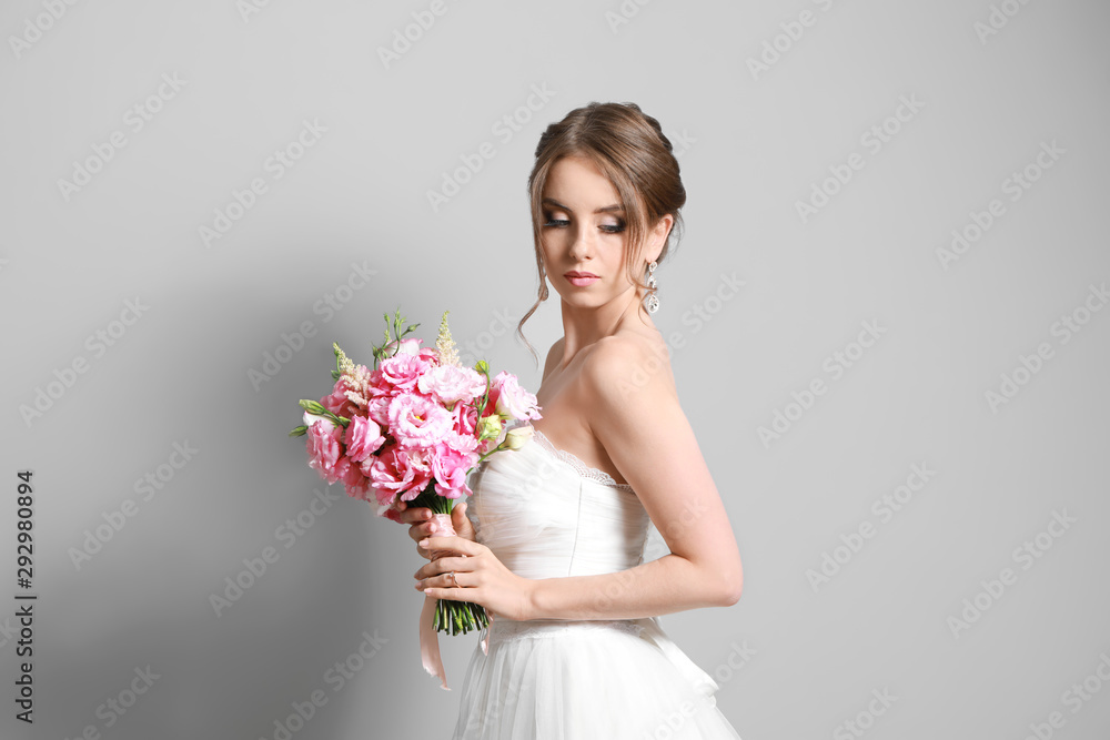 Portrait of beautiful young bride with wedding bouquet on grey background Portrait of beautiful young bride with wedding bouquet on grey background