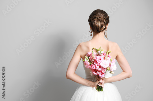 Photography Beautiful young bride with wedding bouquet on grey background,  back view