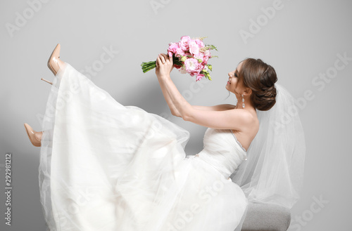 Fotografia Portrait of beautiful young bride with wedding bouquet on grey background