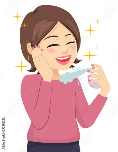 Beautiful young woman spraying bottle of aromatic perfume
