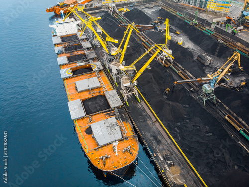 Foto Loading coal anthracite mining in port on cargo tanker ship with crane bucket of train