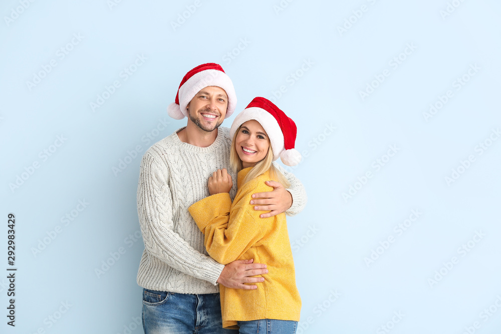 Fototapeta premium Happy couple in Santa hats on color background