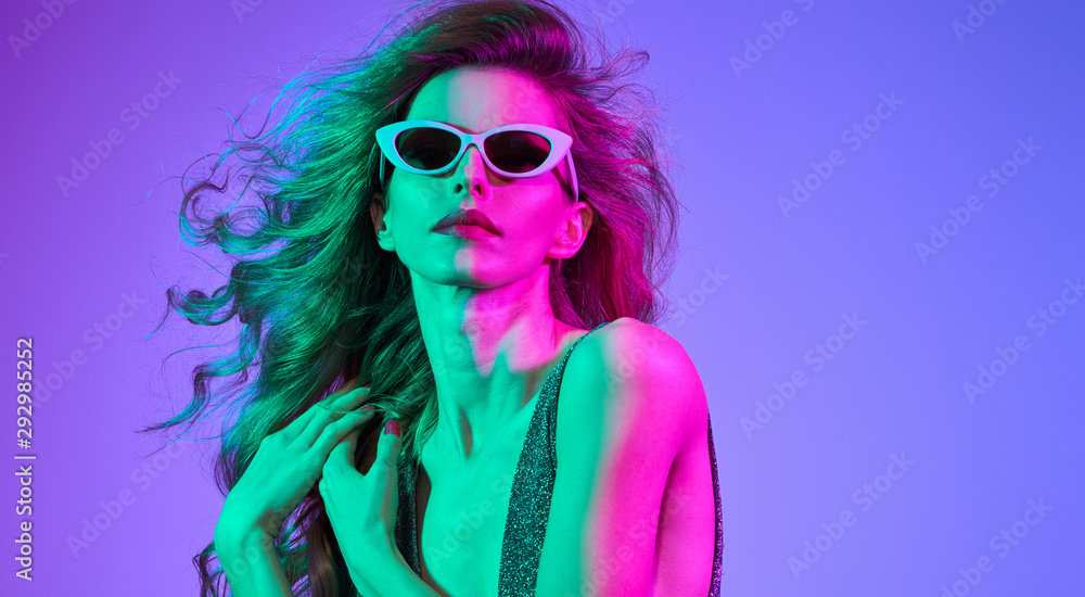Fashion contemporary neon portrait. Beautiful woman in party glamour outfit. Disco summer vibes. Adorable fashionable sexy model girl, trendy stylish hairstyle. Creative art pink purple neon color