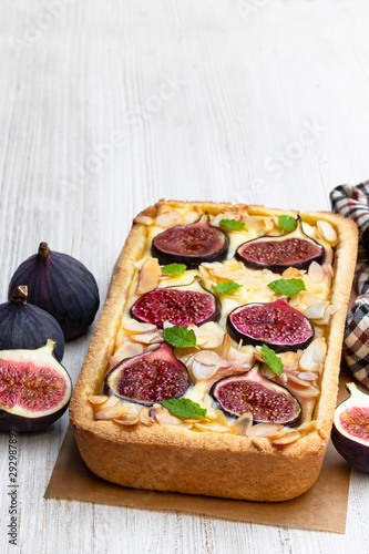 Homemade fig pie with brie cheese and almonds on white wooden table